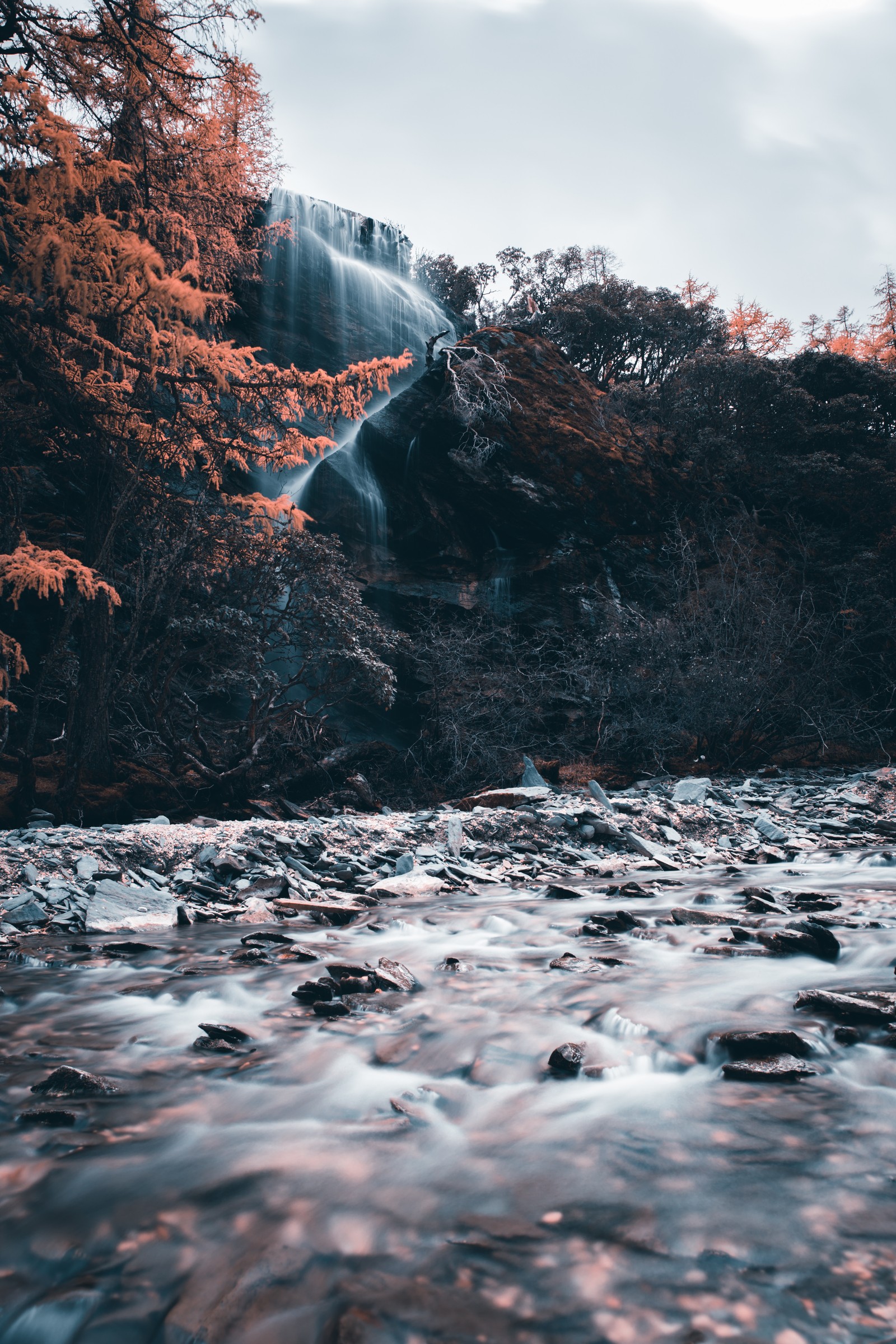 Hay una cascada que fluye por una colina con árboles (recursos hídricos, terreno, rio, desierto, cuerpo de agua)