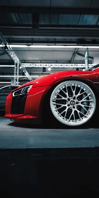 Súper coche rojo elegante que muestra una postura baja con ruedas de aleación blancas en un entorno industrial.