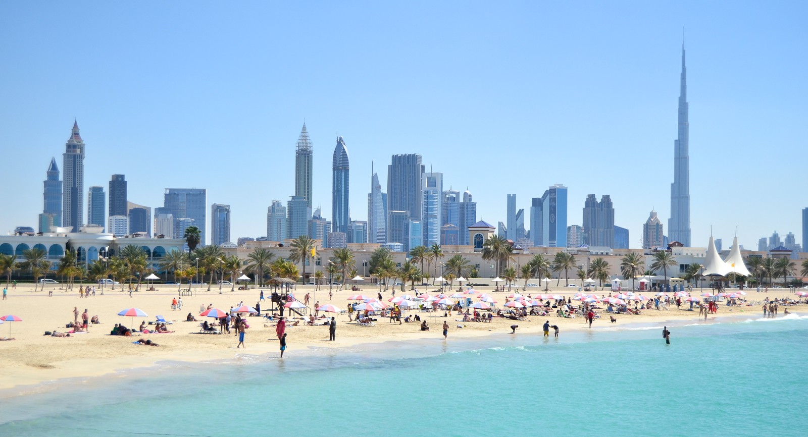 Girafas na praia com uma cidade ao fundo (praia, praia de jumeirah, mar, linha do horizonte, cidade)