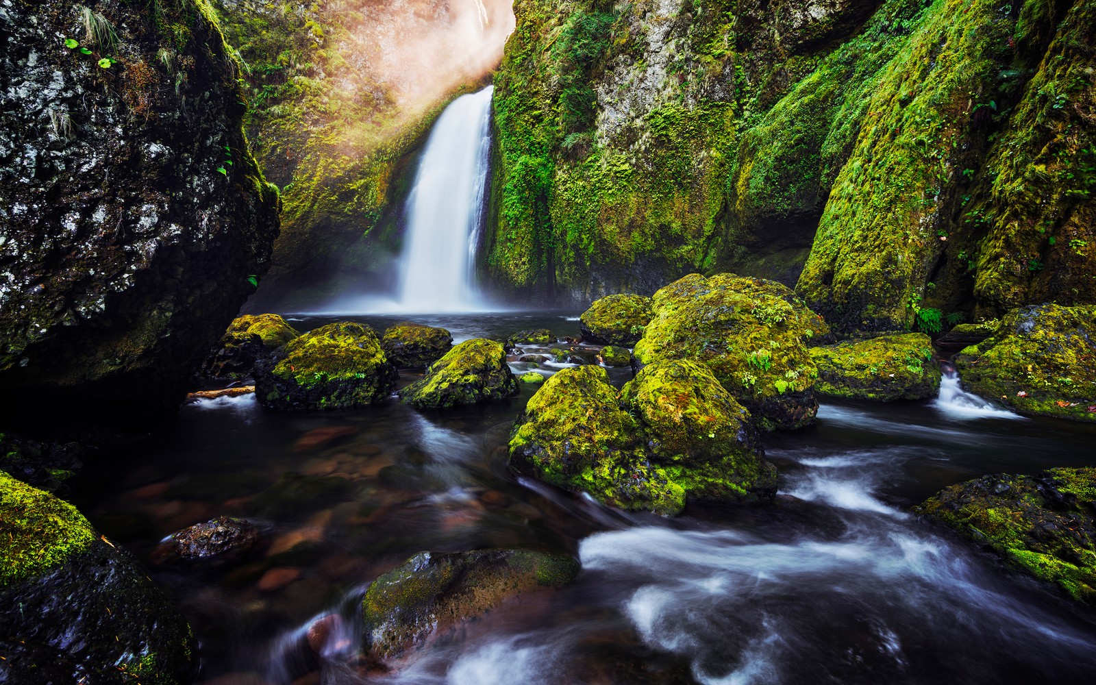 Uma cachoeira fluindo através de uma floresta verde exuberante cheia de pedras (cachoeiras, musgo verde, flux de água, exposição longa, hdr)