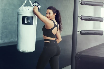 Demi Lovato posando con confianza con un saco de boxeo en ropa deportiva