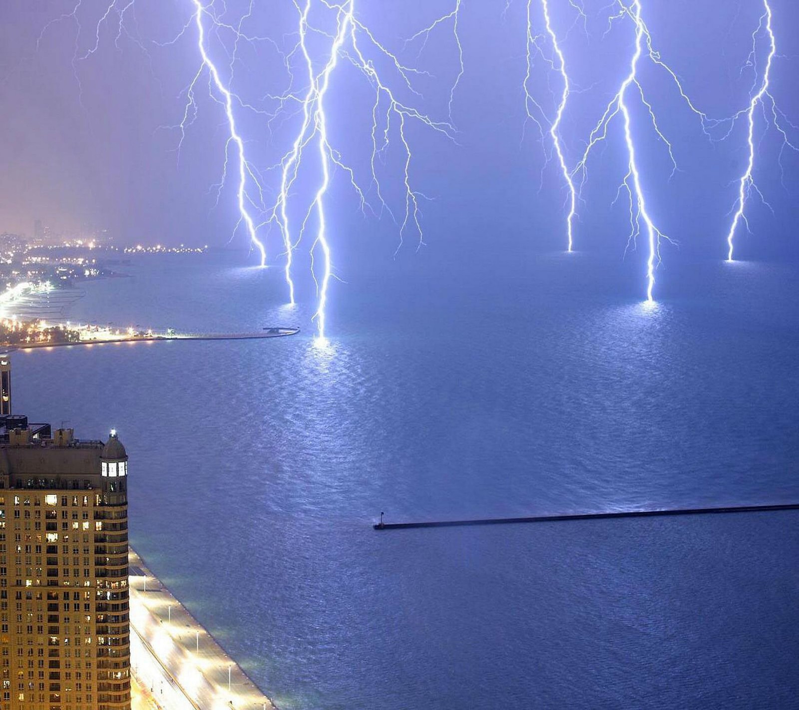 Lightning strikes over the city skyline of a city at night (city, evening, hd, lighting, ocean)