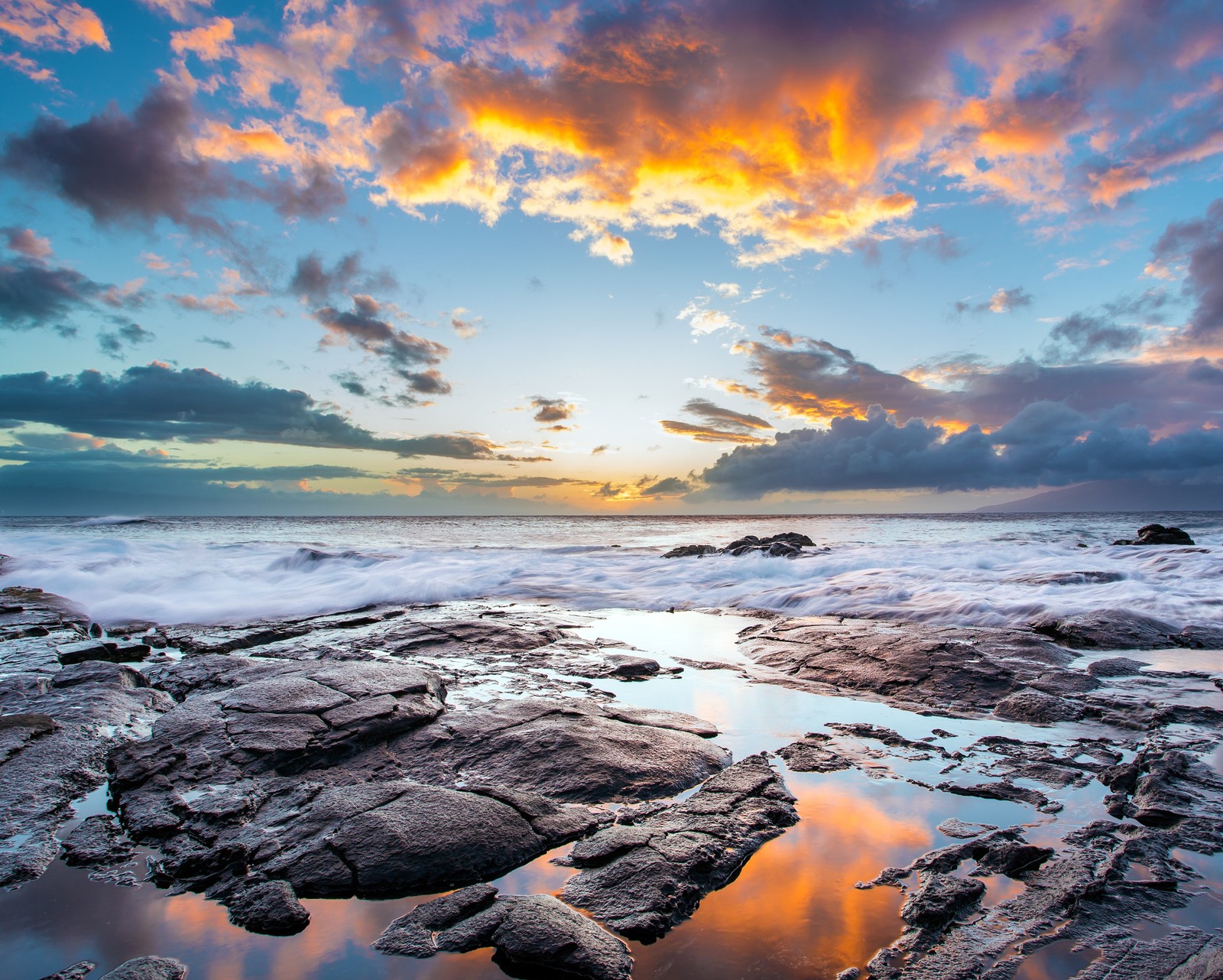 A view of a sunset over the ocean with rocks and water (beach, clouds, coast, island, landscape)