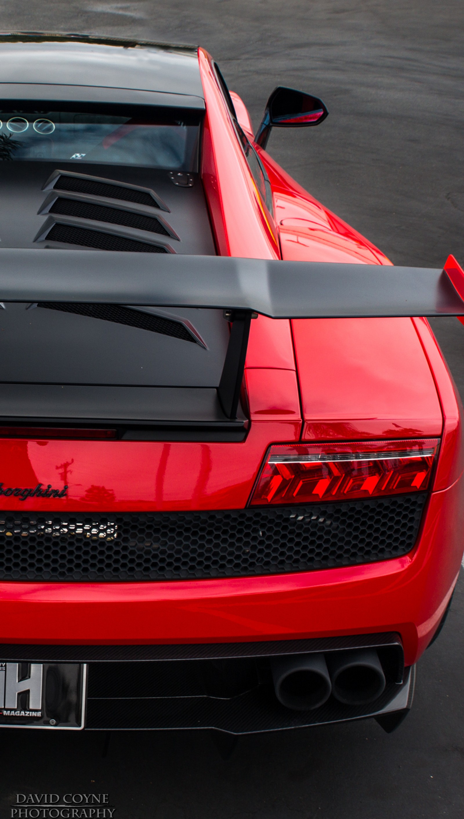 A close up of a red sports car parked in a parking lot (gallardo, lamborghini, sts)