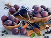 Ciruelas gordas y bayas en cuencos rústicos