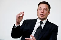 Elon Musk in formal wear discussing business innovations.