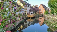 Reflexão encantadora do canal em uma vila pitoresca com casas coloridas e flores em flor.