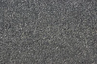 Surface d'asphalte noir texturée avec un mélange de gravier et de granit, mettant en évidence sa composition matérielle utilisée dans la construction routière.