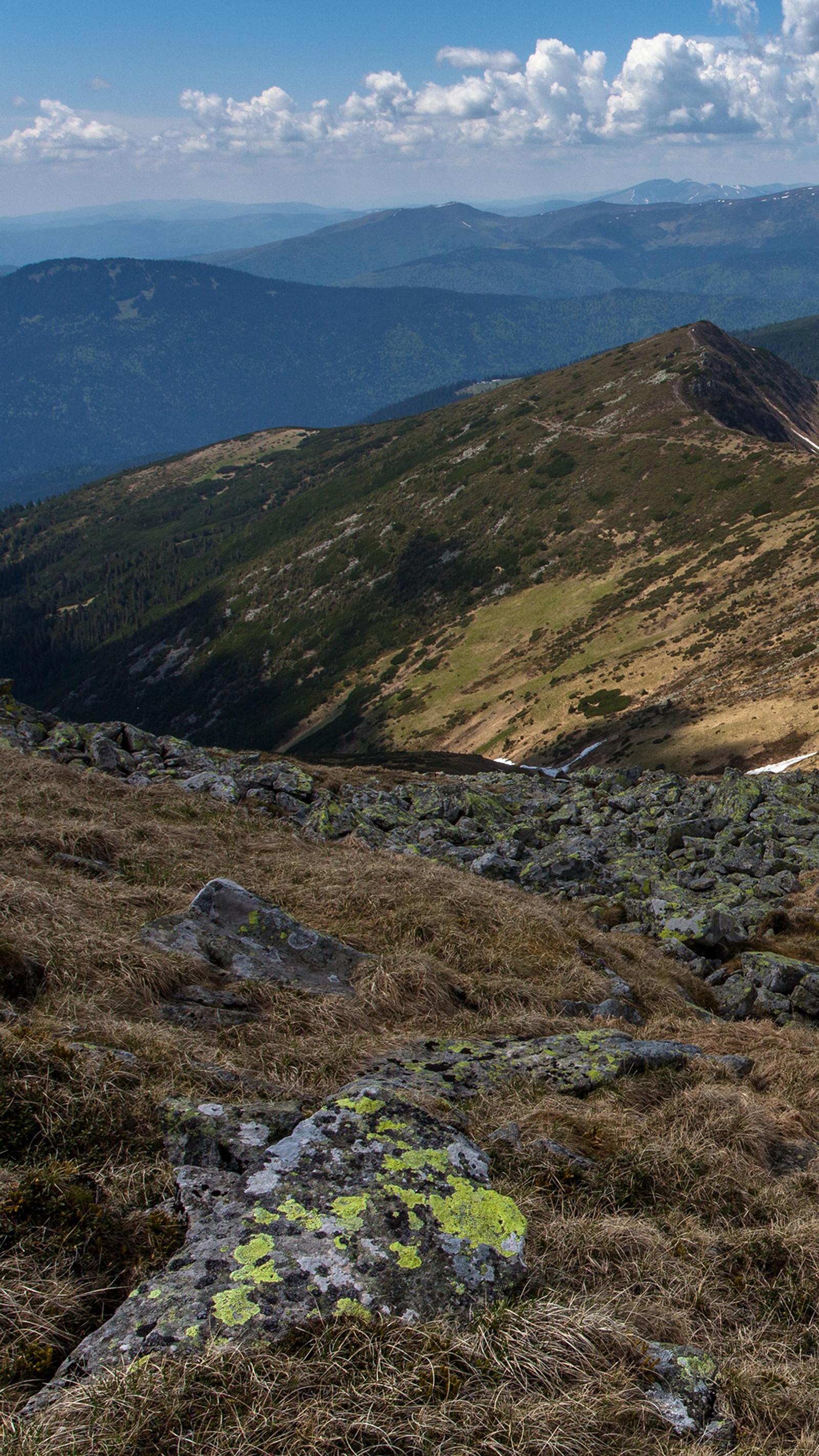 There is a man that is standing on a mountain with a backpack (ridge, cloud, mountain, plant community, ecoregion)