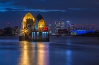 Barrera del Támesis iluminada por la noche con reflejo del horizonte de la ciudad