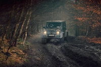 Mercedes-Benz G500 4x4 navegando por un sendero off-road embarrado a través de un bosque brumoso.