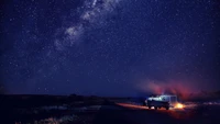 Ciel étoilé au-dessus d'un camping avec un feu de camp