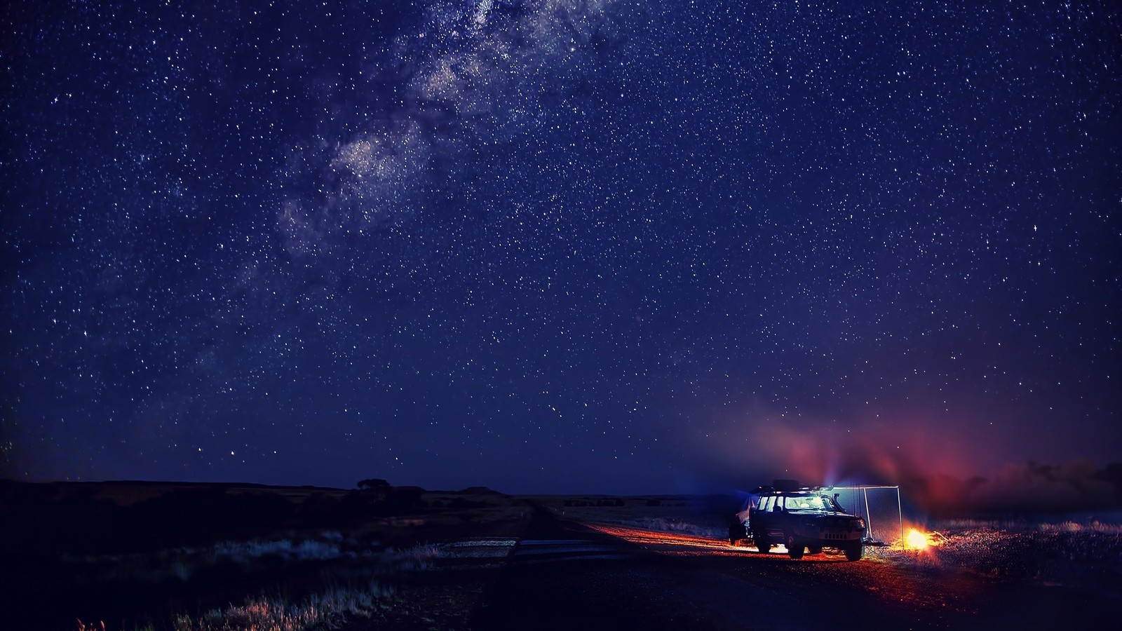 Um veículo árabe estacionado em uma estrada sob um céu estrelado (noite, céu, estrelas, cenário, campismo)