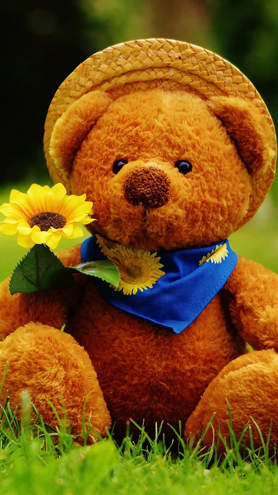 Tierno oso de peluche sosteniendo un girasol, vestido con una bufanda azul y un sombrero de paja en un entorno de hierba.