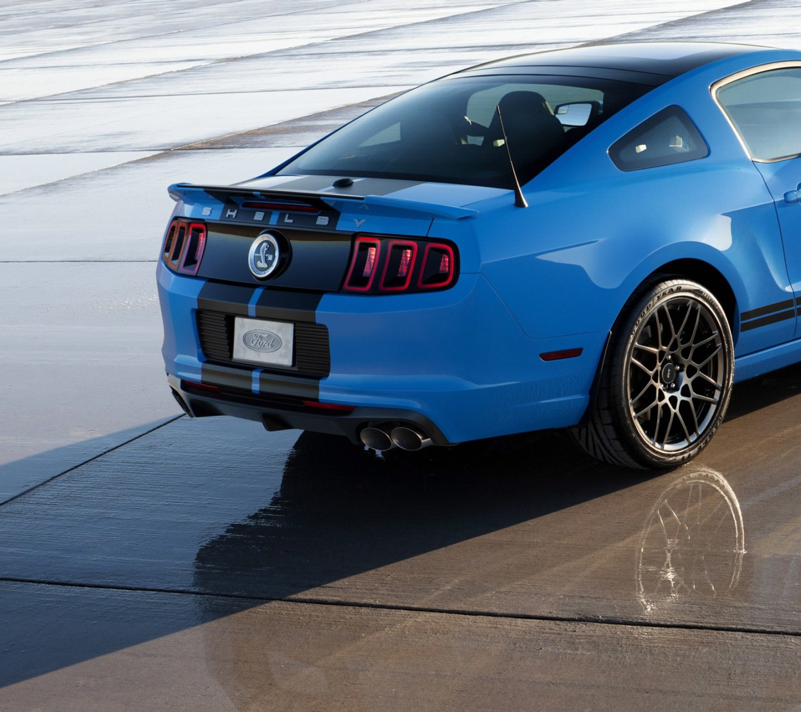 Un primer plano de un mustang azul estacionado en una pista mojada (azul, coche, ford, gt500, músculo)