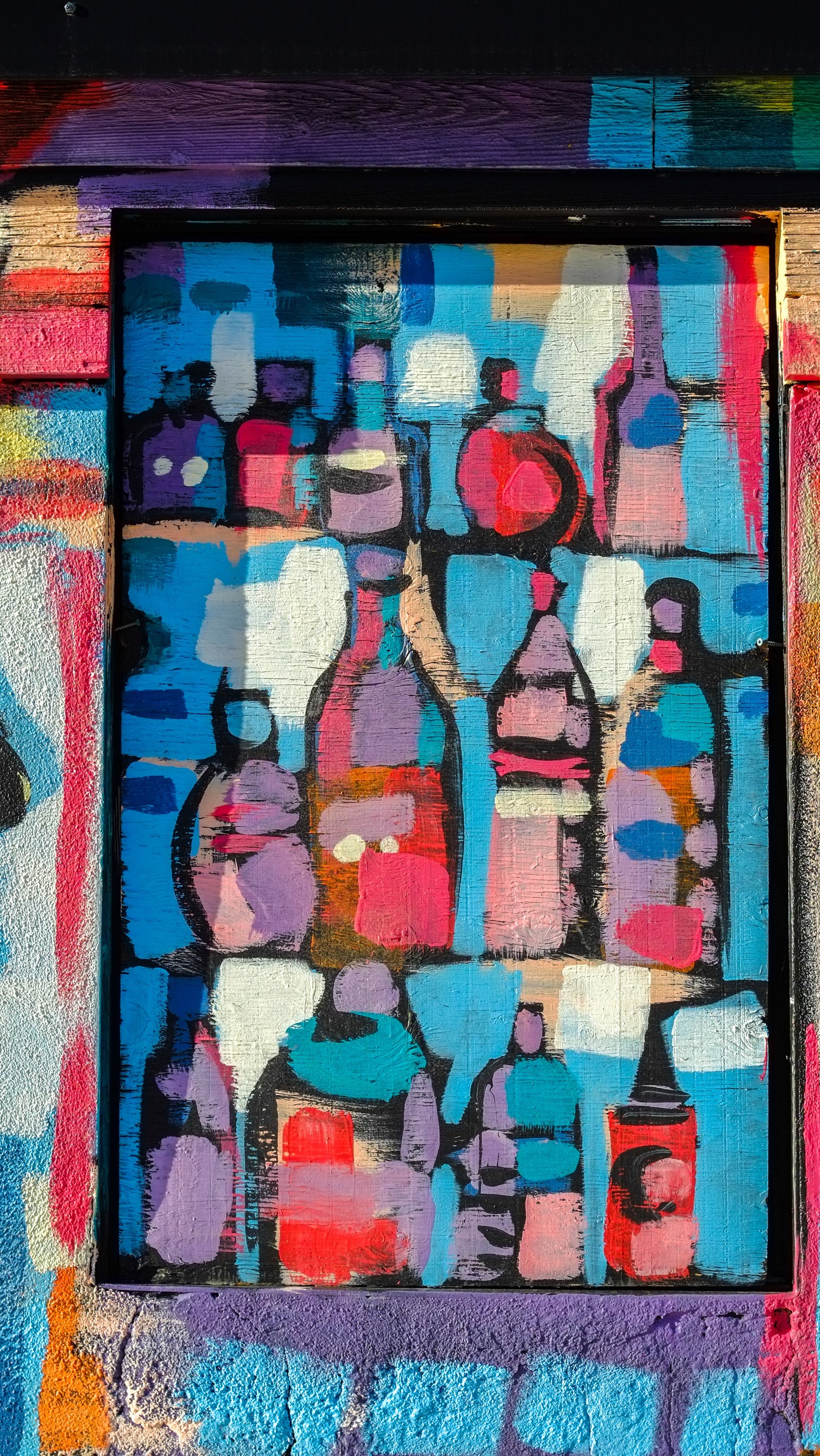 Graffiti on a wall with a window and a picture of bottles (alone, art, blue, bottle, colors)