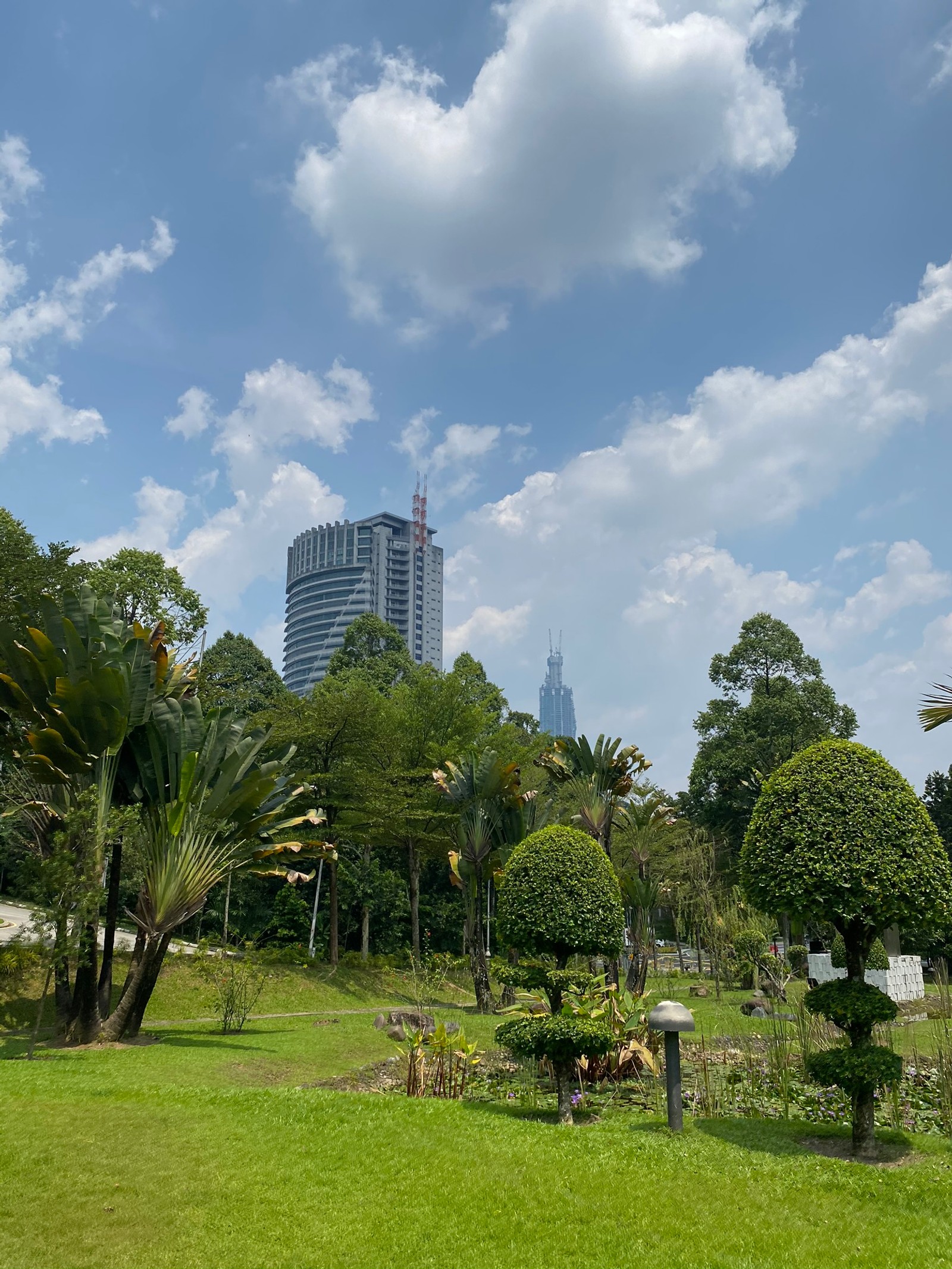 There is a park with a lot of trees and bushes (vegetation, daytime, cloud, tree, tower block)