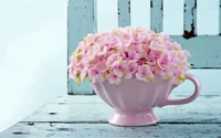 A charming arrangement of delicate pink hydrangeas in a vintage pink mug, set on a rustic wooden table.