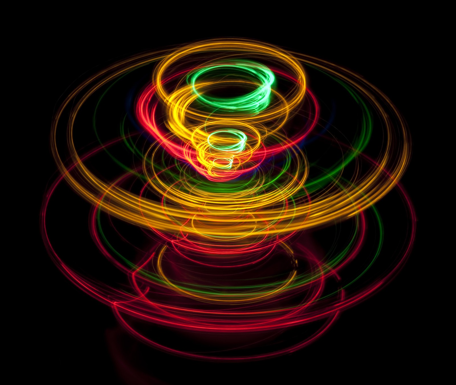 A close up of a colorful light painting of a stack of rings (pattern, rotation, top, green, neon)