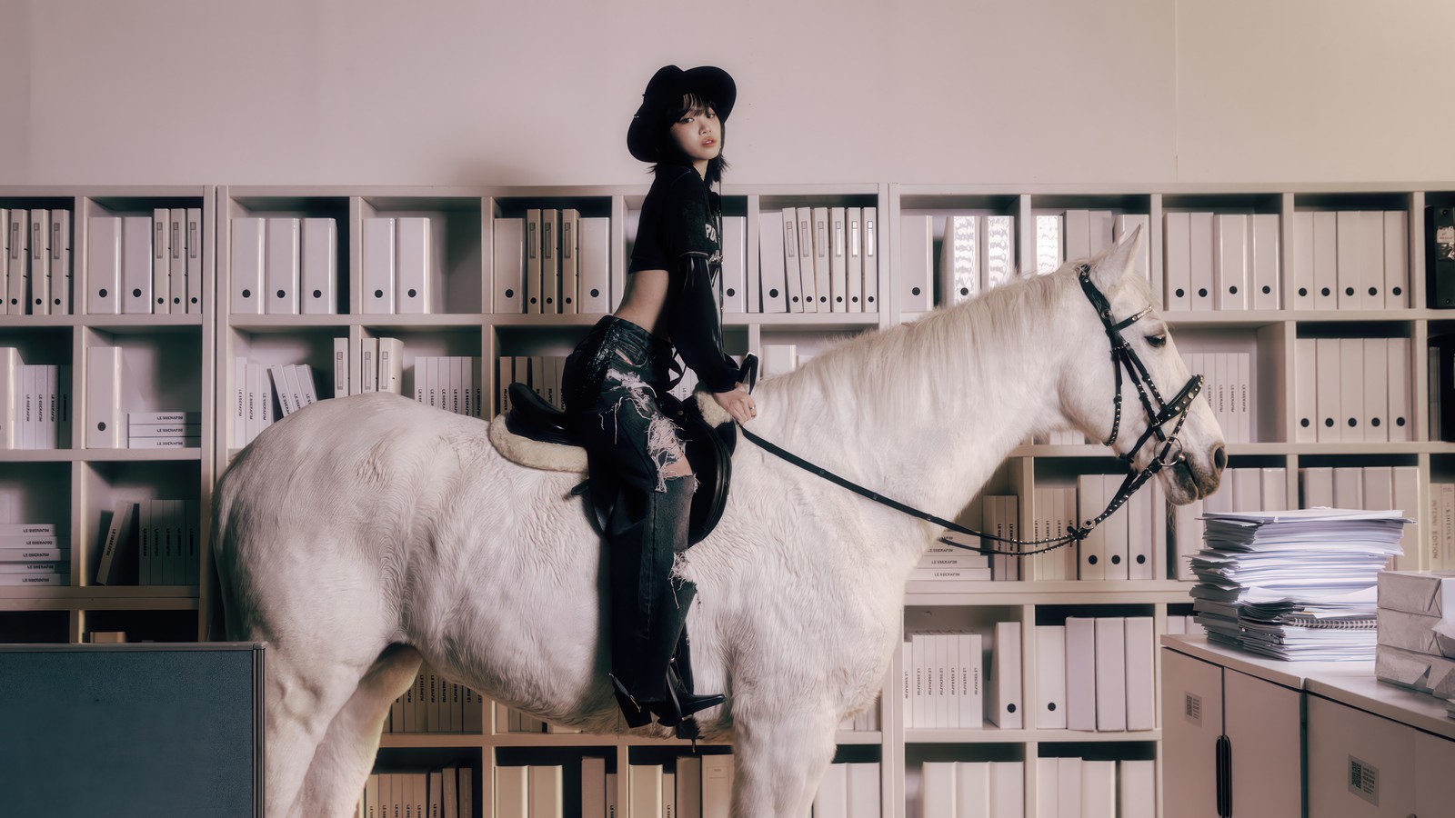 There is a woman riding a horse in a room full of books (le sserafim, 르세라핌, kpop, korean, girl group)