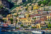 Vibrante vila costeira de Positano, com edifícios coloridos, uma praia movimentada e uma deslumbrante paisagem montanhosa.