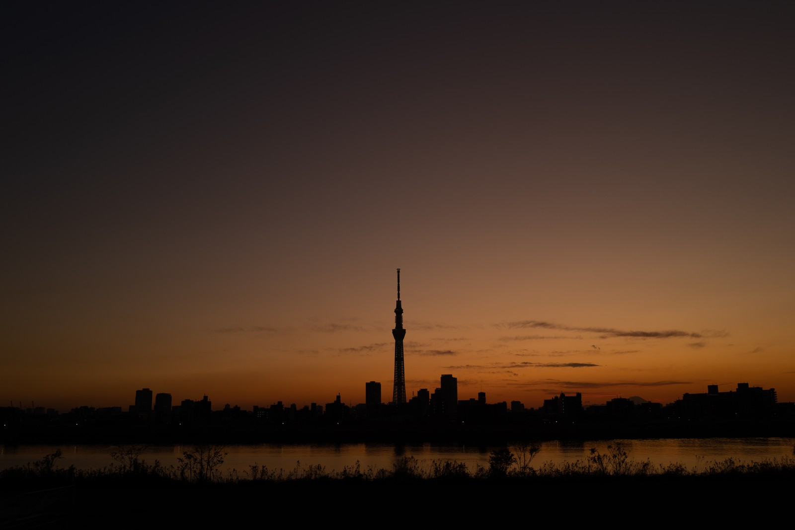 Vue de la ligne d'horizon d'une ville au coucher du soleil avec un lac au premier plan (silhouette, soir, crépuscule, coucher de soleil, matin)