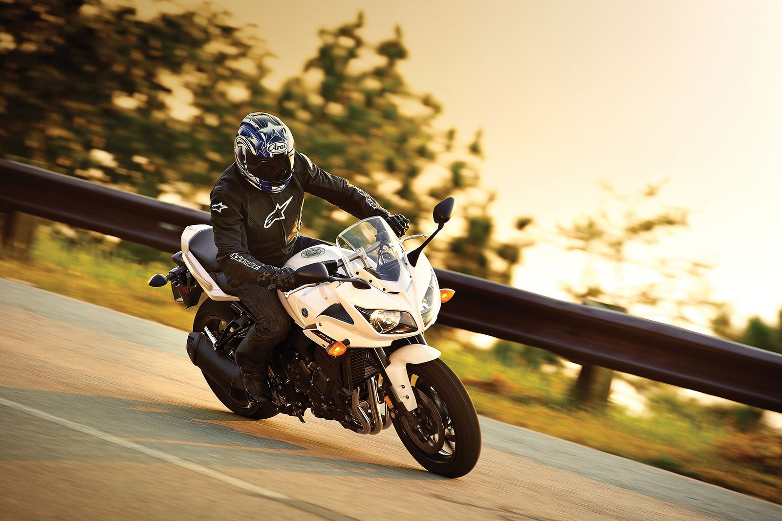 Arafed man riding a white motorcycle down a road next to a forest (yamaha motor company, motorcycle, car, motorcycling, supermoto)