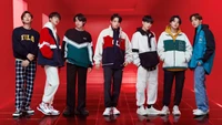 Membres de BTS en tenues Fila élégantes sur un fond rouge audacieux