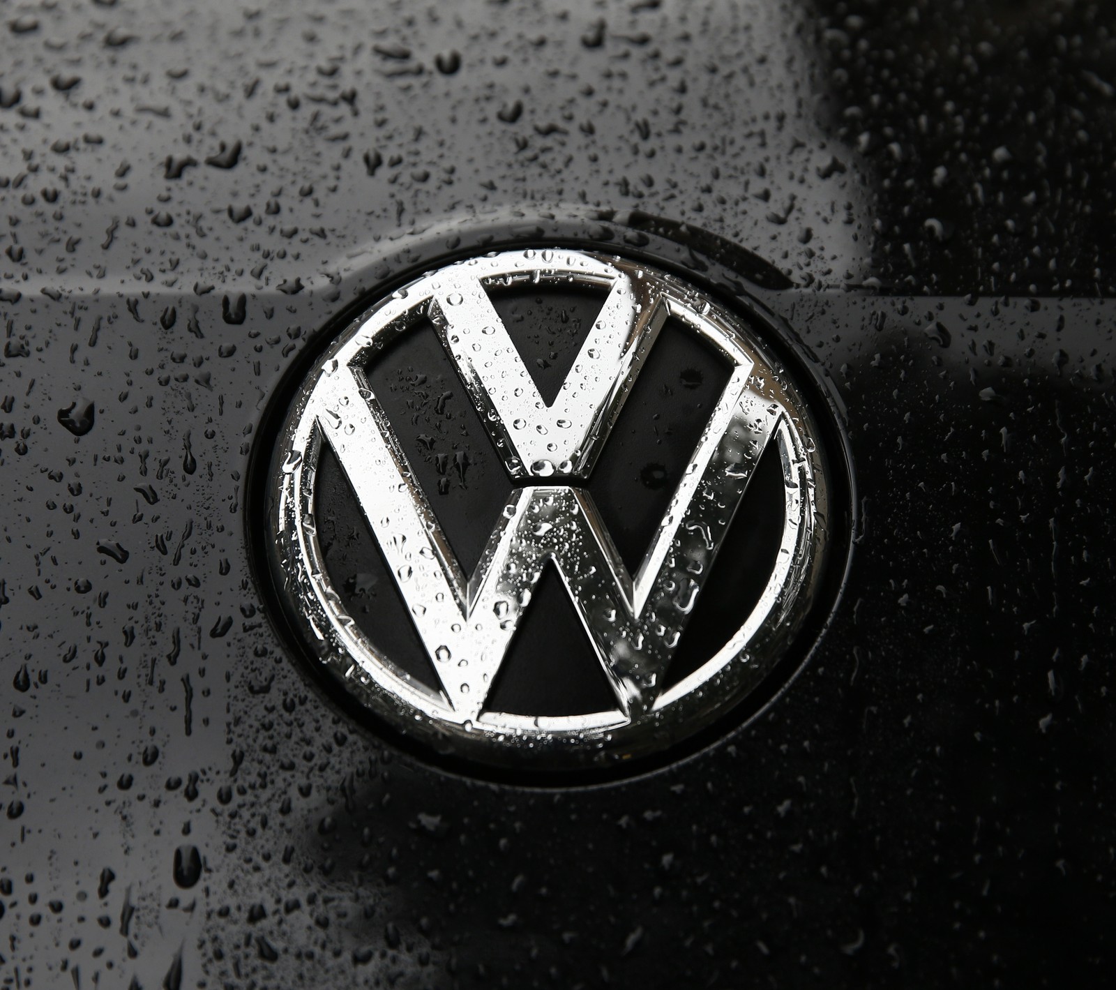 A close up of a vw logo on a black car (bora, golf, jetta, logo, rain)