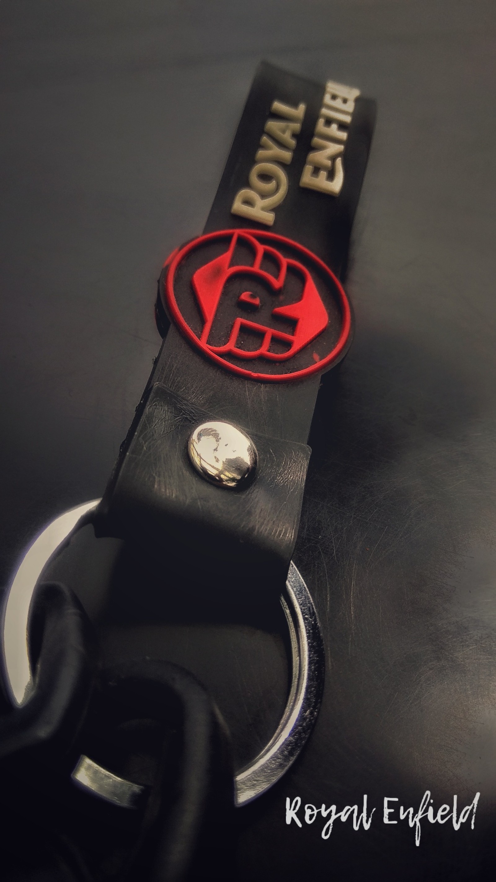 A close up of a key chain with a red and black logo (bullet, cool, enfield, keycahin, royal)