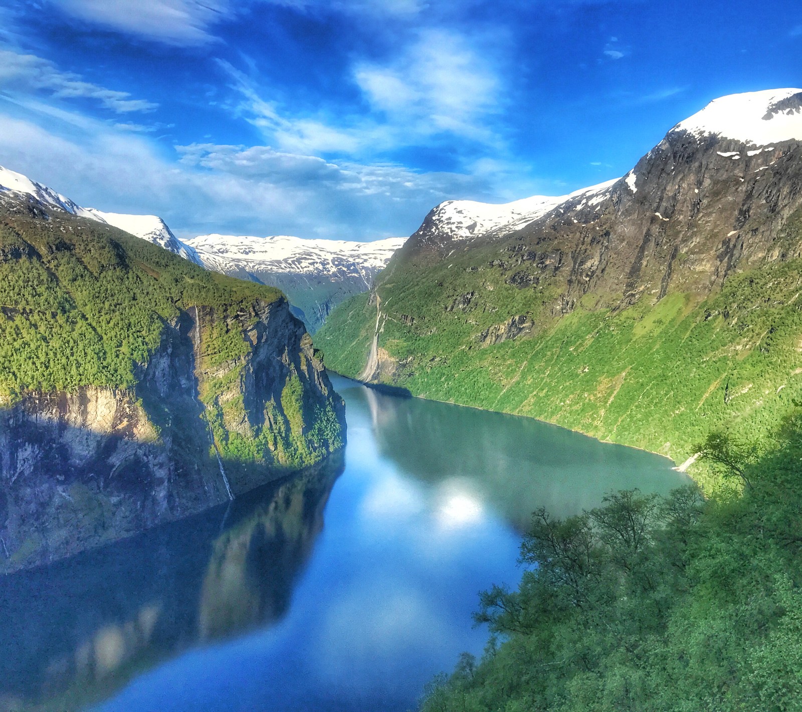 Imagem aérea de um lago de montanha com uma montanha ao fundo (fiorde, geiranger, noruega)