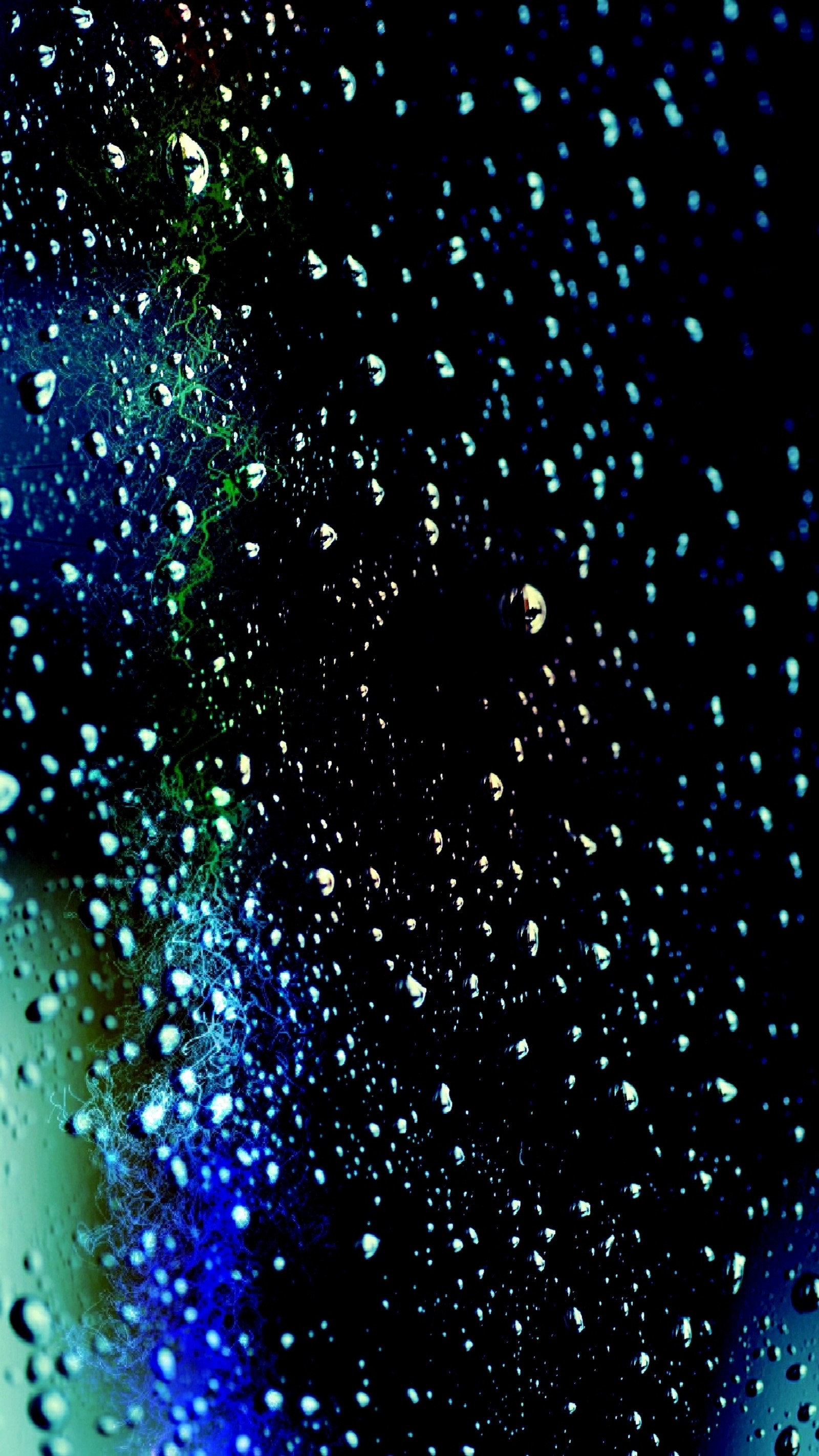 A close up of a window with water droplets on it (blue, bubbles)