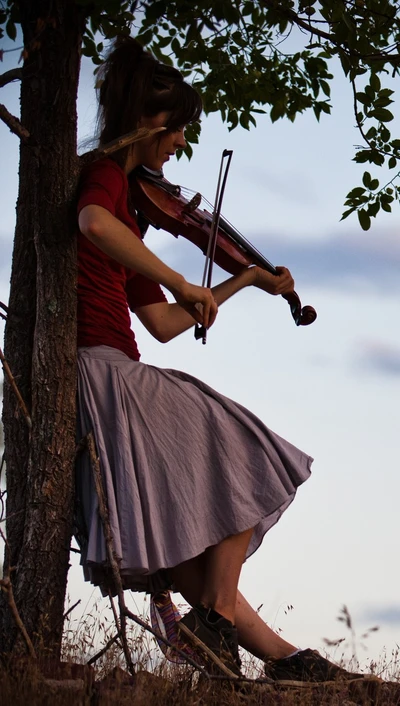 Geigerin Lindsey Stirling spielt unter einem Baum bei Dämmerung