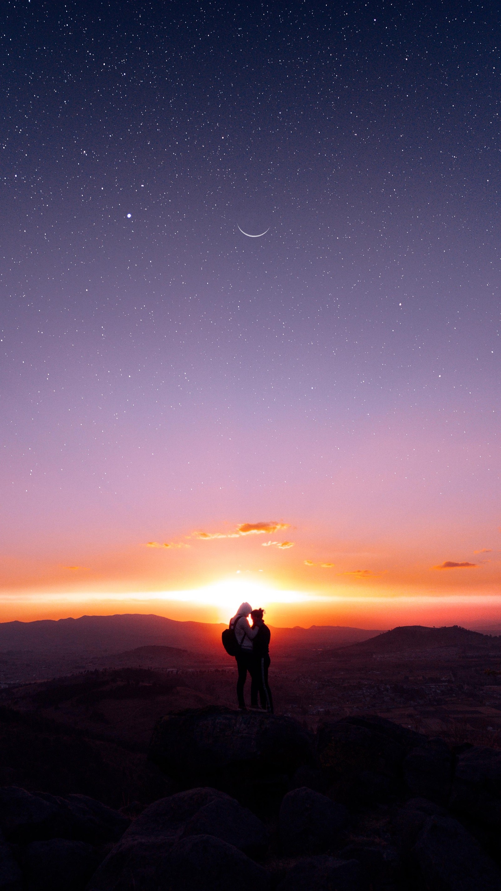 Há duas pessoas em pé em uma montanha ao pôr do sol (nuvem, atmosfera, ecorregião, luz, resplendor)