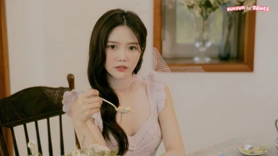 Hyojung de Oh My Girl disfrutando de un momento en una mesa encantadora, vestida con un delicado vestido y exudando elegancia.