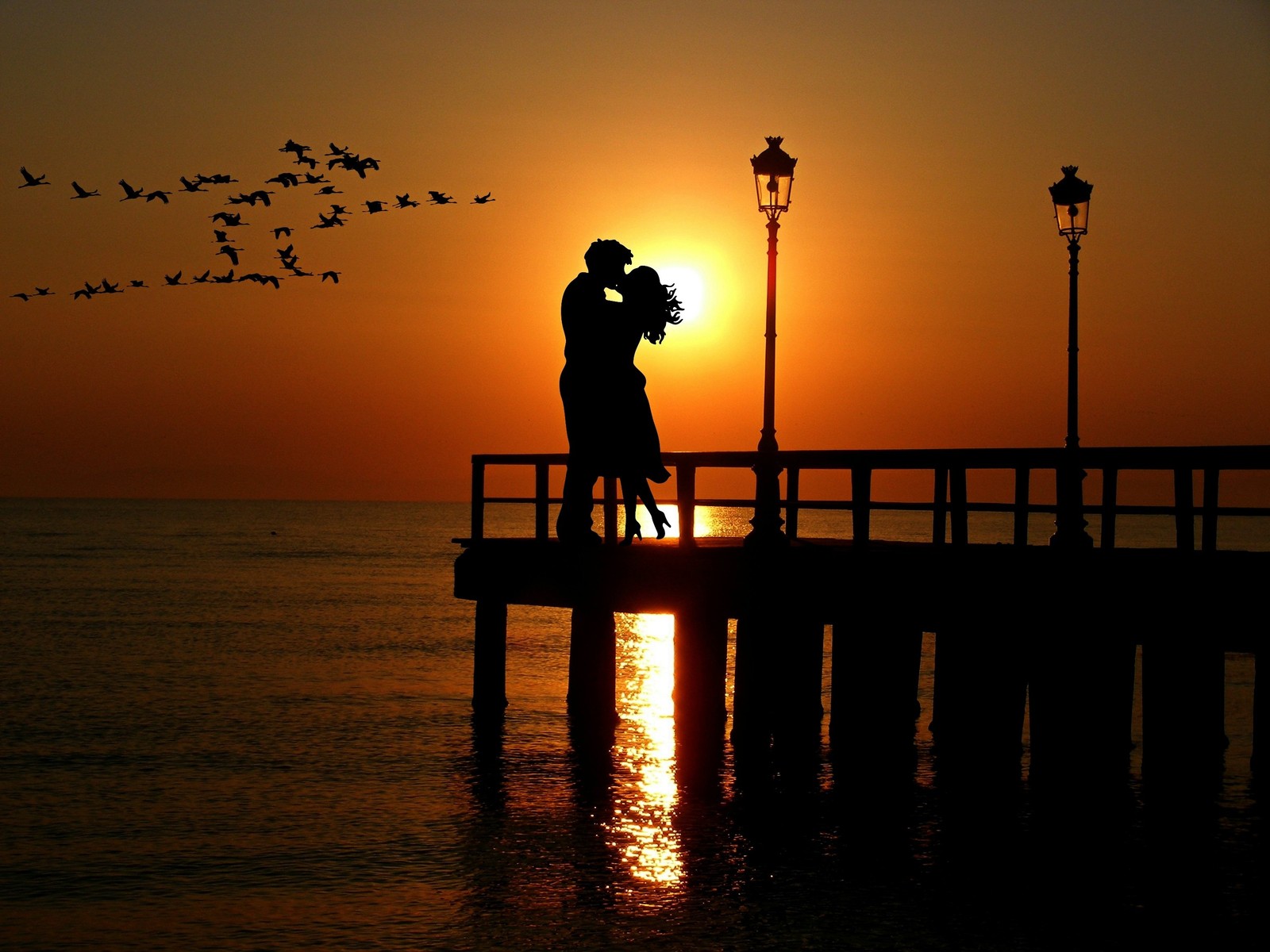 Uma imagem árabe de um casal se beijando em um cais ao pôr do sol (casal, céu laranja, beijo romântico, por do sol, silhueta)