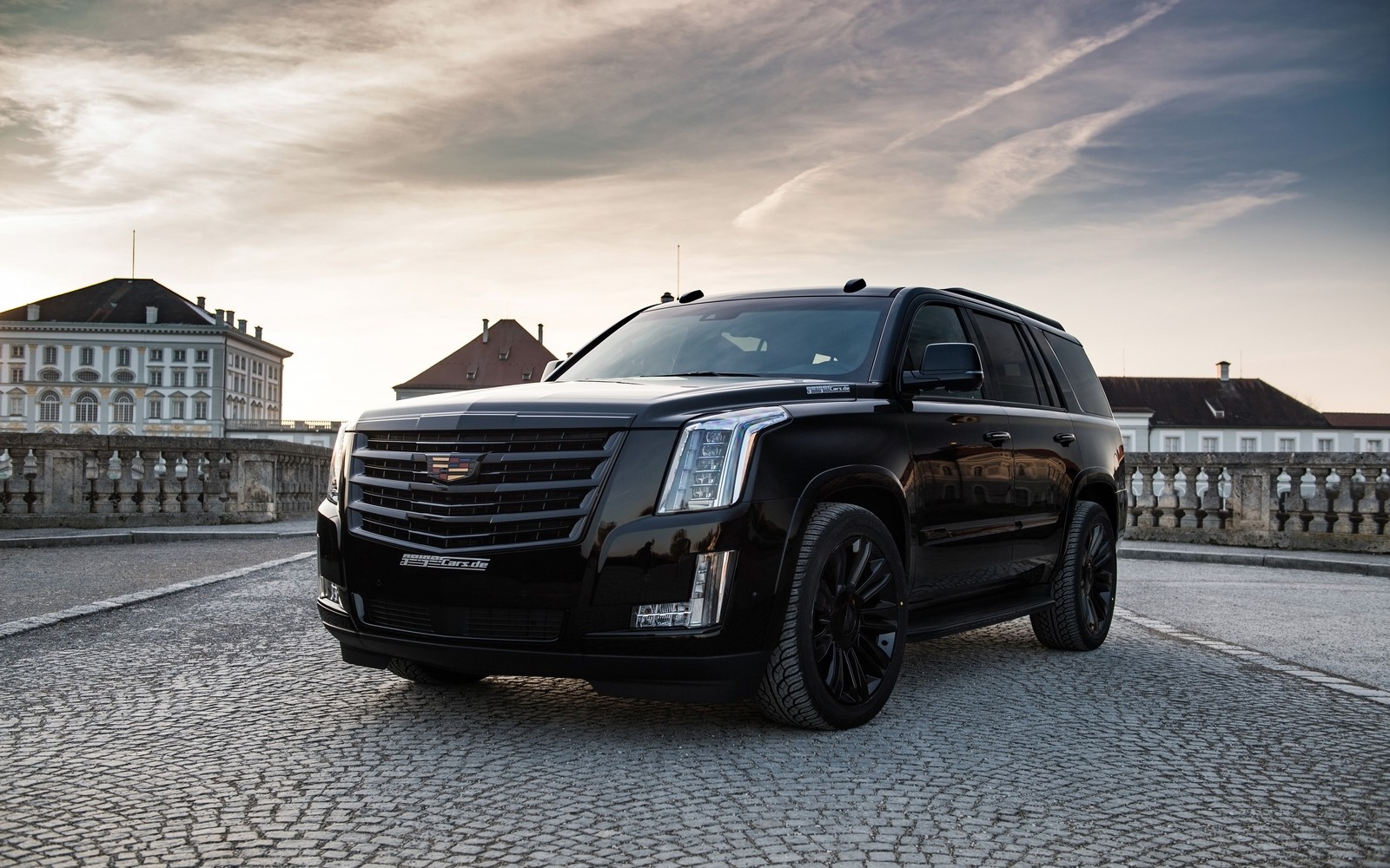 A close up of a black cadillac suv parked on a cobblestone road (america, black, cadillac, escalade, tuned)