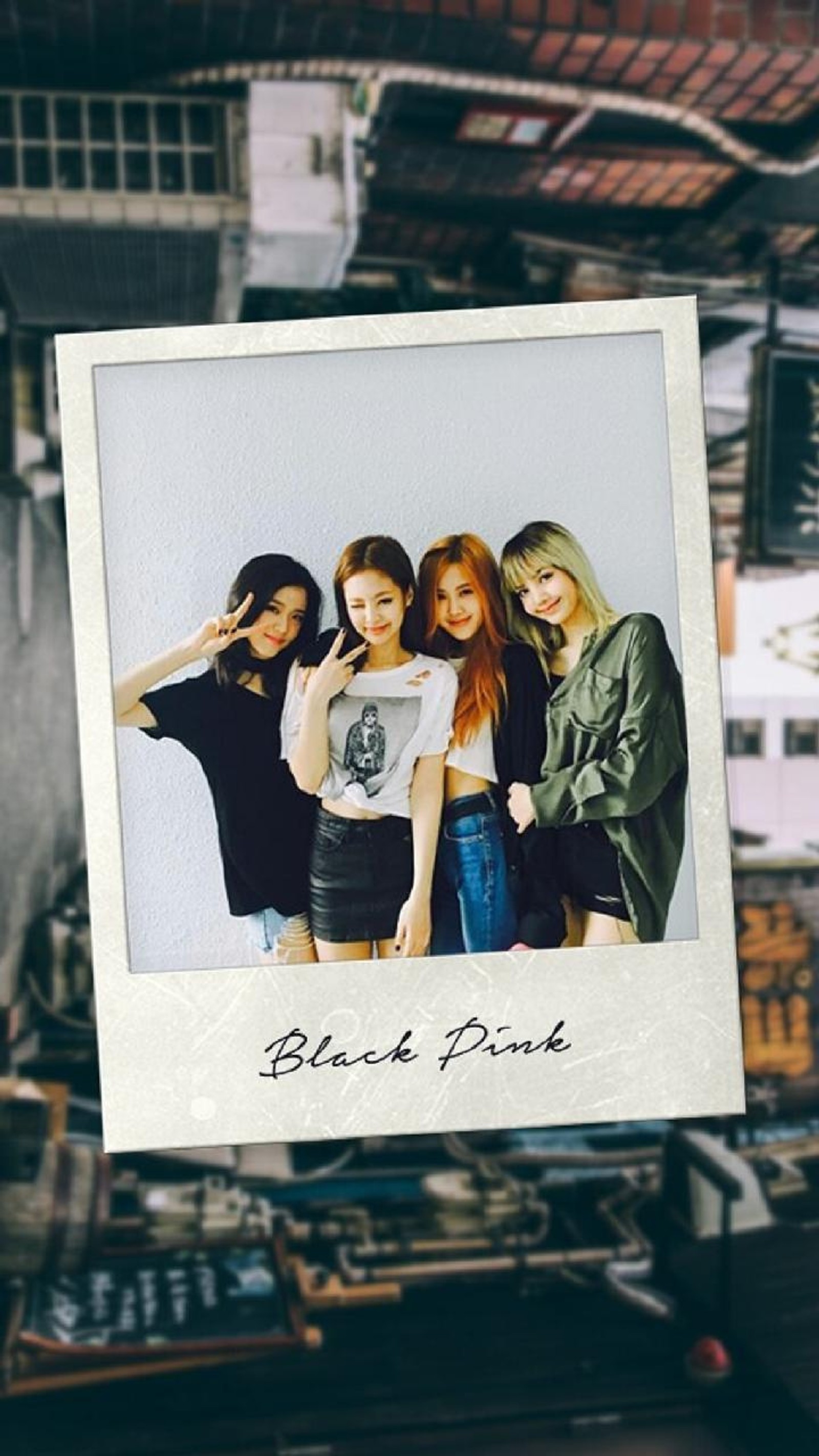 Une personne tenant une photo polaroid de quatre filles dans un entrepôt (lisa, rose, jisoo, noir, k pop)