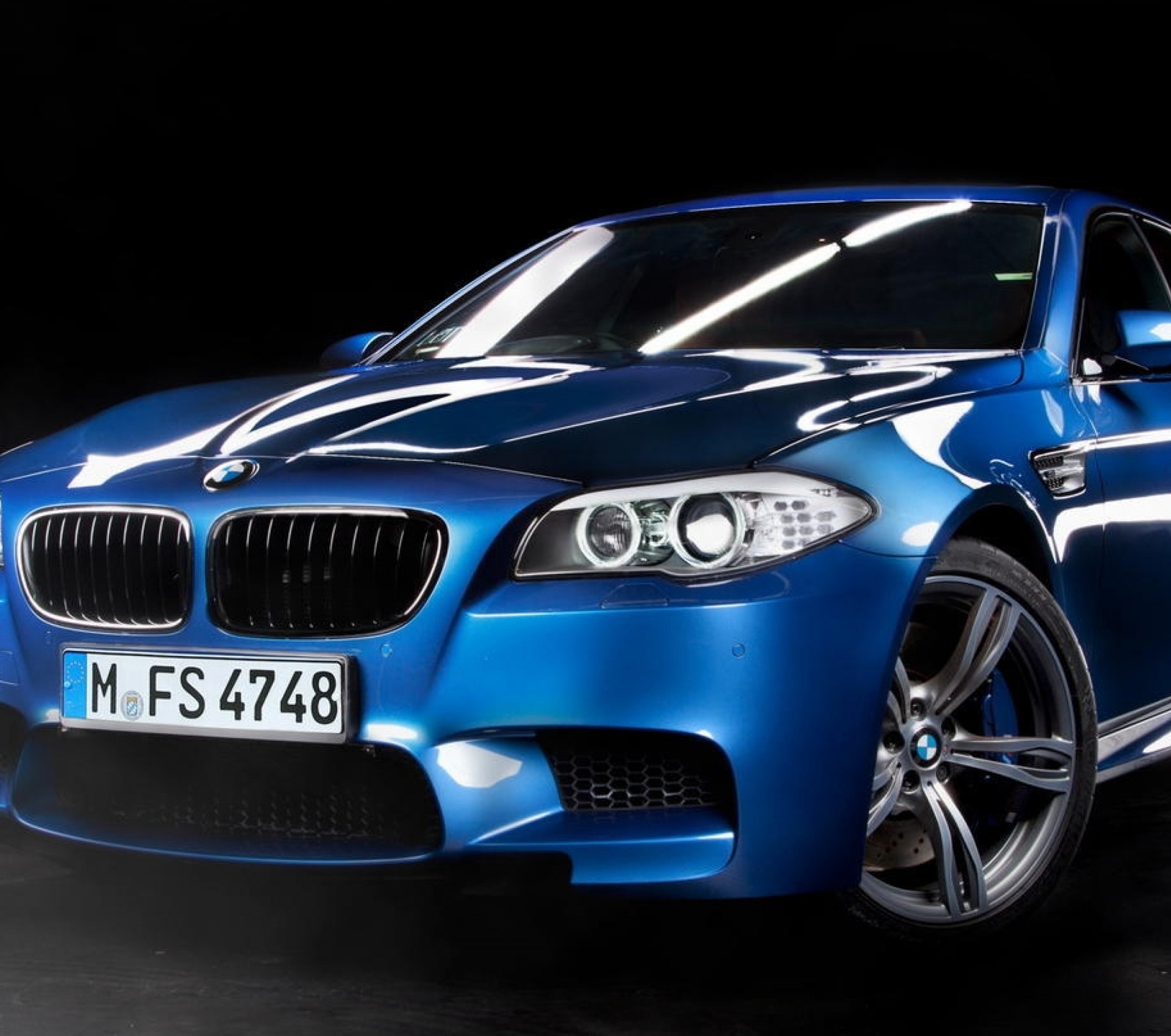 A close up of a blue bmw m5 parked in a dark room (bmw, car, vehicle)