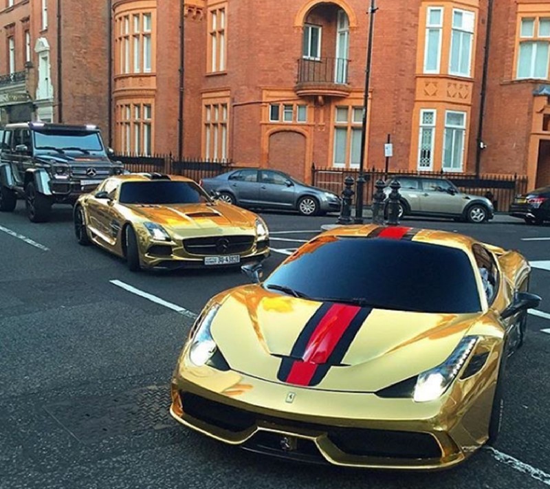 Vista aérea de coches deportivos dorados estacionados en un aparcamiento frente a un edificio (oro, mercedes)