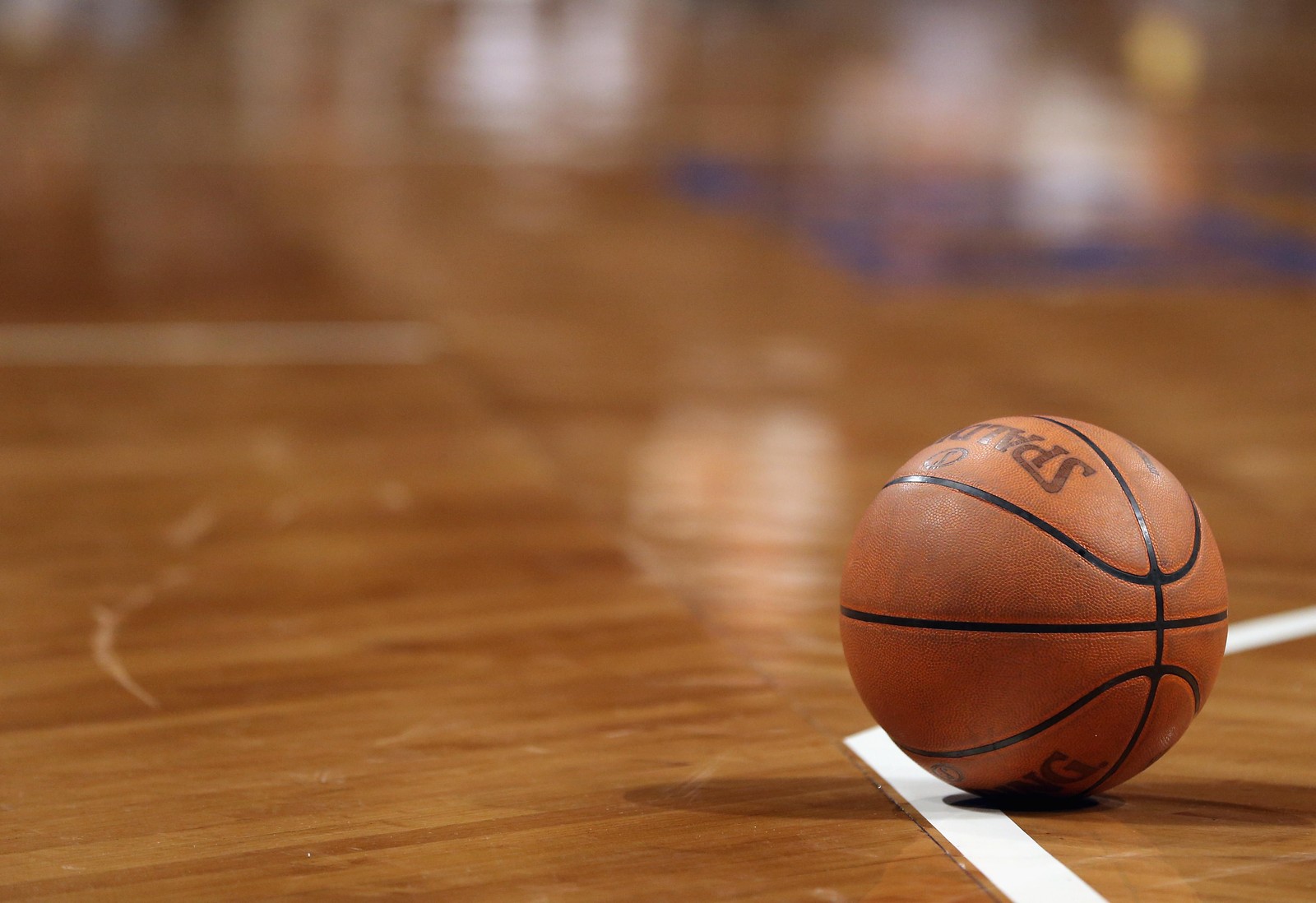 Un primer plano de un balón de baloncesto en una cancha con una línea (baloncesto, cancha de baloncesto, madera dura, pelota, madera)