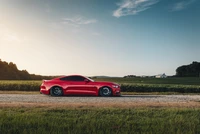 Elegante Ford Mustang vermelho estacionado em uma estrada de cascalho com uma paisagem pitoresca e céu claro.