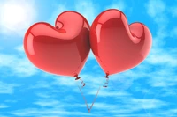 Dos globos rojos en forma de corazón flotando en un cielo azul