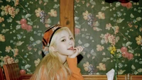 Jiheon von fromis_9 posiert charmant vor einem vintage-blumigen Hintergrund und zeigt ihren verspielten Stil und ihr strahlendes Lächeln.