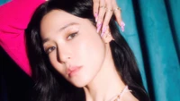 Tiffany Young présente une pose frappante avec des ongles glamour et une tenue vibrante, incarnant l'essence de l'élégance K-pop.