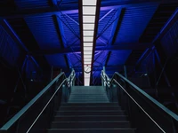 Iluminación azul simétrica que resalta escaleras urbanas por la noche