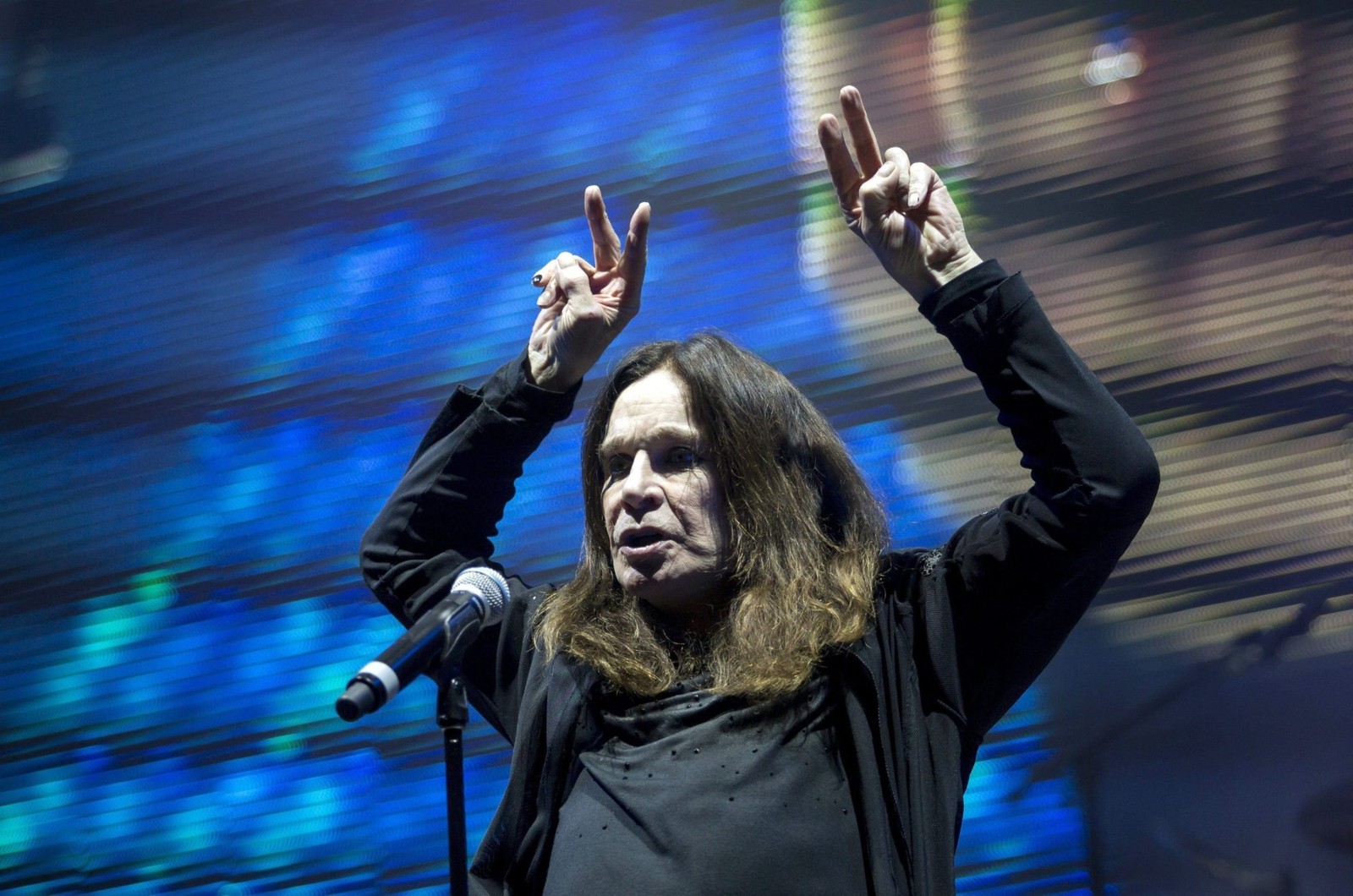 Hombre de cabello largo y camiseta negra sosteniendo un micrófono (ozzy osbourne, black sabbath, heavy metal, músico, desempeño)