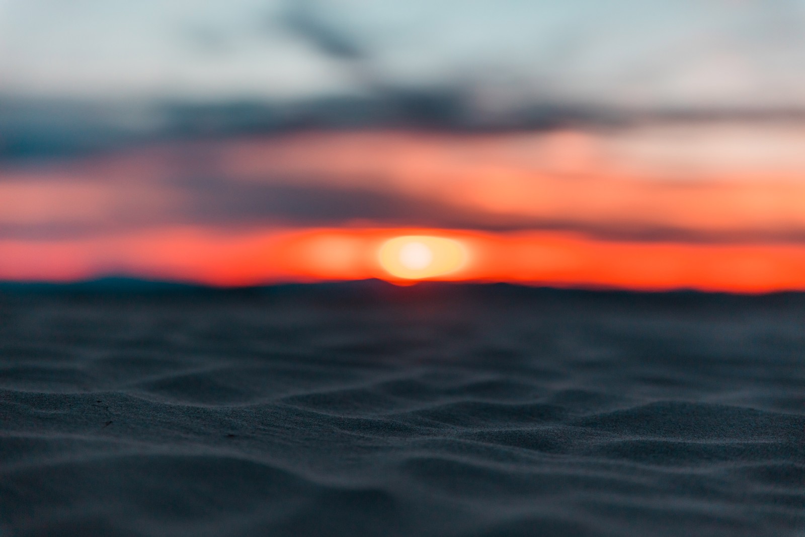 Image floue d'un coucher de soleil sur une plage avec une petite bouteille de bière (coucher de soleil, lever de soleil, désert, horizon, eau)