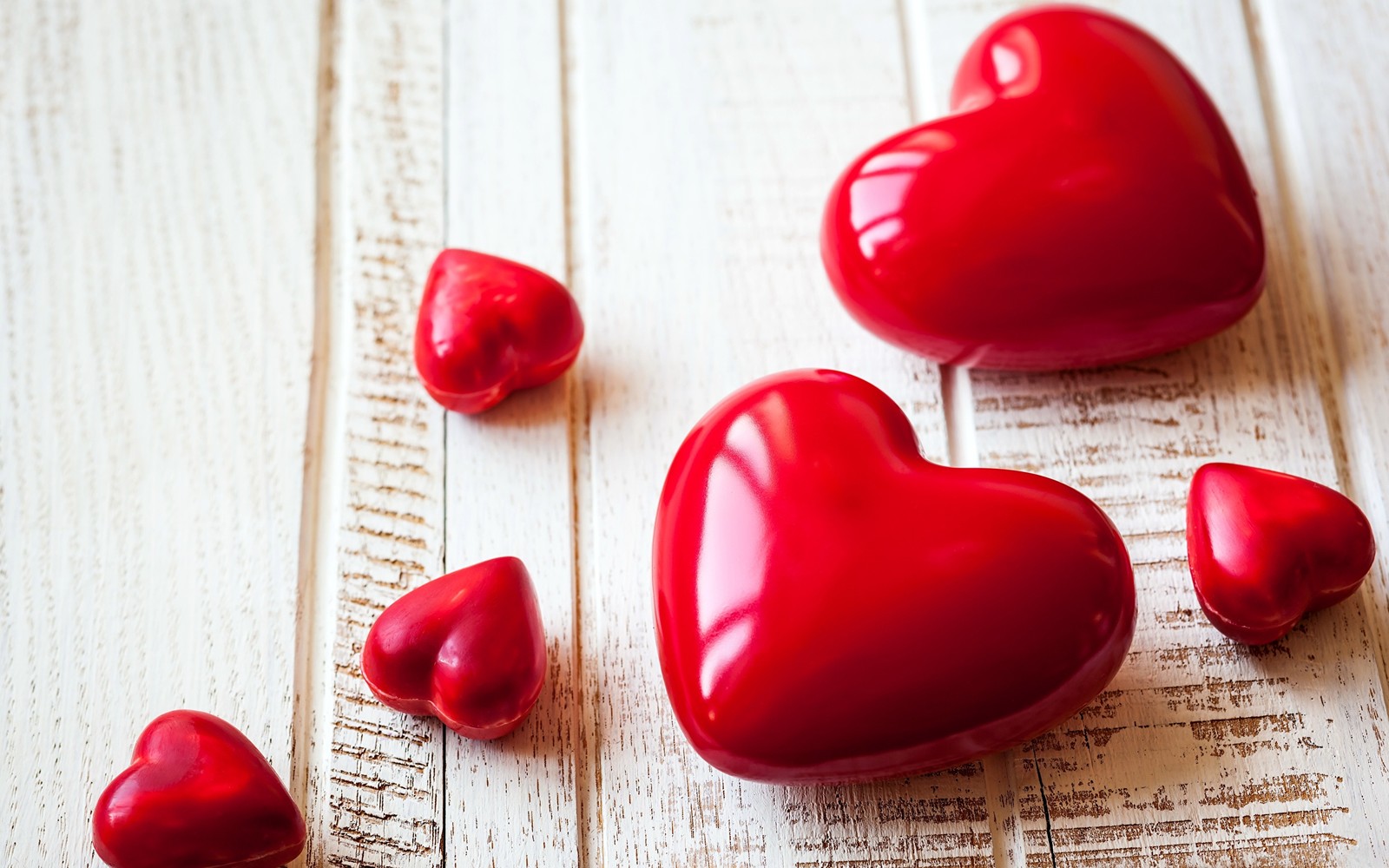 Plusieurs cœurs rouges sont éparpillés sur une surface en bois blanc (cœur, amour, saint valentin, romance, rencontres)