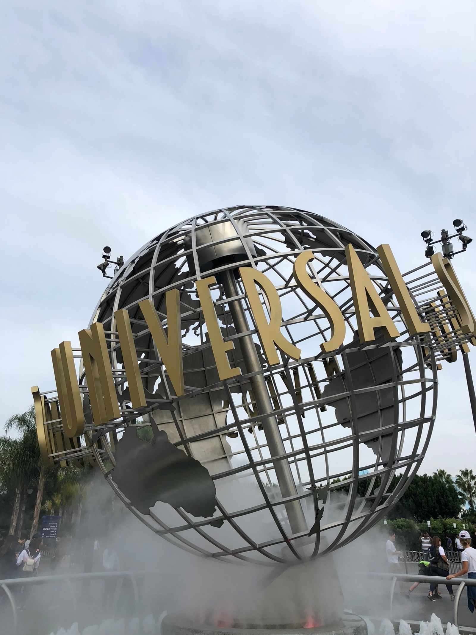 Há um grande globo de metal com uma placa que diz universal. (atração turística, parque de diversões, mundo, design urbano, esfera)